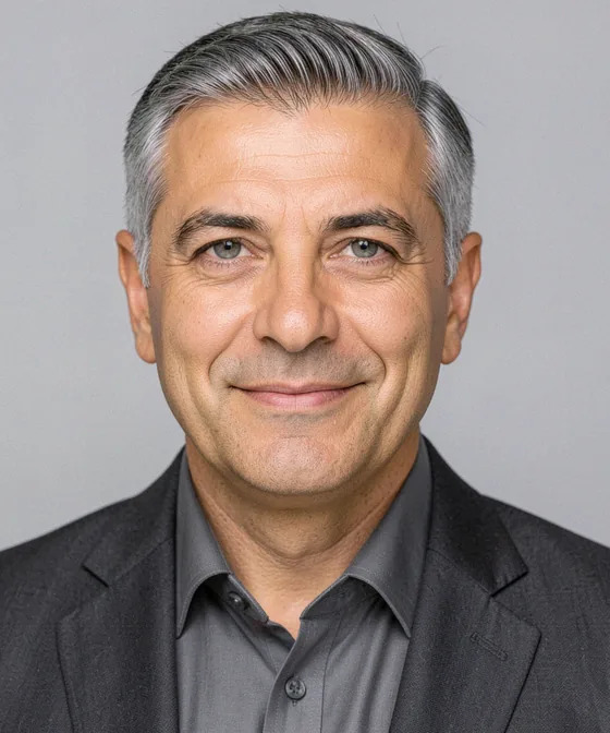 Breites Business-Porträt — Korrektes Business-Porträt: natürliches Lächeln mit geschlossenem Mund, Blick in die Kamera, Kopf-und-Schulter-Ausschnitt, hellgrauer Hintergrund